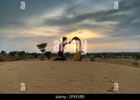 Nicht identifizierter Mann wirft mit Sand in der Luft in der Wüste jaisalmer, rajasthan. Stockfoto