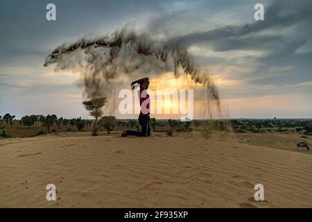 Nicht identifizierter Mann wirft mit Sand in der Luft in der Wüste jaisalmer, rajasthan. Stockfoto