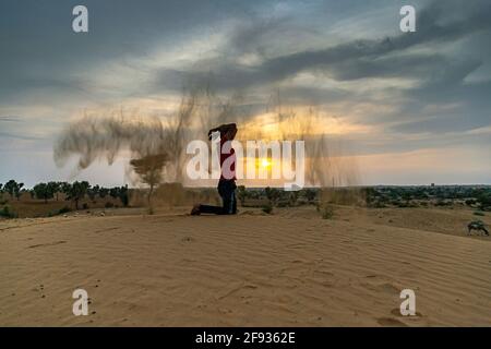 Nicht identifizierter Mann wirft mit Sand in der Luft in der Wüste jaisalmer, rajasthan. Stockfoto