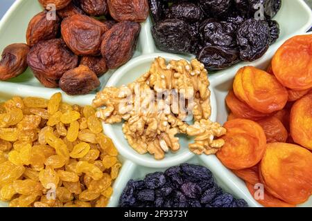 Getrocknete Früchte und Nüsse Draufsicht. Getrocknete Aprikosen, Rosinen, Pflaumen und Walnüsse auf der Platte aus nächster Nähe. Stockfoto