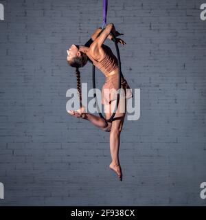Weibliche Zirkus-Aerialistin akrobatin trainiert auf dem Reifen. Starke Frau macht Bewegung in der Luft Stockfoto