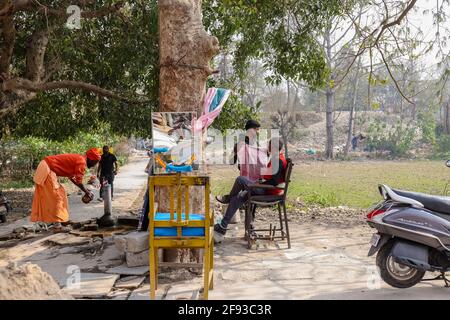 HARIDWAR, UTTARAKHAND, INDIEN - FEBRUAR 2021 : ein nicht identifizierter Barber auf der Straße von Haridwar in der Nähe von Har KI Pauri Ghat den Kunden rasieren. Stockfoto