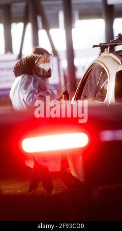 Hannover, Deutschland. April 2021. Ein Helfer testet die Insassen eines Autos im Testzentrum am Zoo mit einem Schnelltest auf das neuartige Corona-Virus. Das Robert Koch-Institut (RKI) berichtet weiterhin über einen Anstieg der neuen Coronainfektionen in Deutschland. Quelle: Julian Stratenschulte/dpa/Alamy Live News Stockfoto