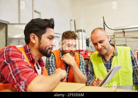 Lagerarbeiter und Kommissionierer besprechen einen Auftrag im Werkslager Stockfoto