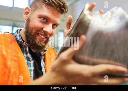 Junger Metallarbeiter mit Produkt oder Metallkomponente während der Qualität Kontrolle im Werk Stockfoto