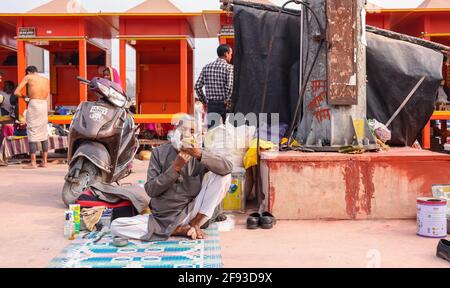 HARIDWAR, UTTARAKHAND, INDIEN - FEBRUAR 2021 : ein nicht identifizierter Barber auf der Straße von Haridwar in der Nähe von Har KI Pauri Ghat den Kunden rasieren. Stockfoto