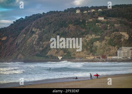 San Sebastian, Spanien - 15. März 2021: Surfer am Strand von Zurriola an einem Wintertag in San Sebastian Stockfoto