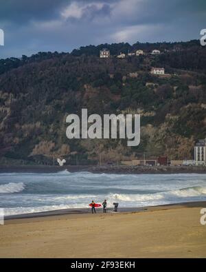 San Sebastian, Spanien - 15. März 2021: Surfer am Strand von Zurriola an einem Wintertag in San Sebastian Stockfoto