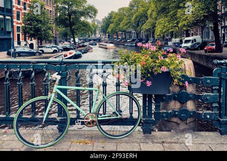 Amsterdam Kanal mit Booten und Fahrrädern auf einer Brücke Stockfoto