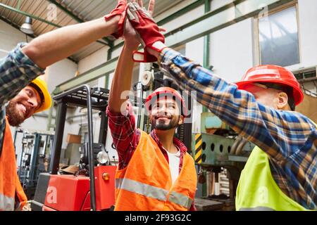 Grippe glücklich Lagerarbeiter im Lager macht hoch fünf für Motivation vor dem Gabelstapler Stockfoto
