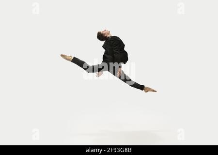 Mann in legerer Kleidung springt und tanzt isoliert auf weißem Hintergrund. Kunst, Bewegung, Aktion, Flexibilität, Inspirationskonzept. Flexibel Stockfoto