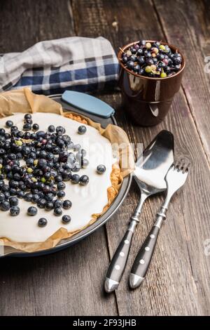 Frischer Käsekuchen mit wilden Blaubeeren auf rustikalem Hintergrund. Selektiver Fokus. Geringe Schärfentiefe. Stockfoto