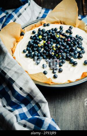 Frischer Käsekuchen mit wilden Blaubeeren auf rustikalem Hintergrund. Selektiver Fokus. Geringe Schärfentiefe. Stockfoto