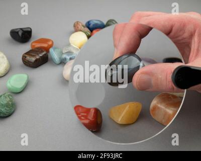 Erforschung von Halbedelsteinen mit einer Lupe. Farbige Edelsteine unter der Lupe Stockfoto
