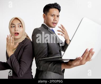 Zwei junge Kollegen aus dem Unternehmen überraschten den Laptop Stockfoto