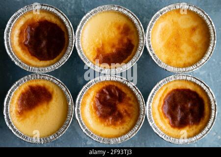 Frisch hausgemachter Flan oder Creme Karamell in ihren Formen auf blauem rauem Hintergrund. Draufsicht Stockfoto