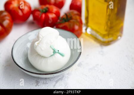 Burrata-Käse, Tomaten und Olivenöl, um einen traditionellen italienischen Salat zu machen. Weichfokus Stockfoto