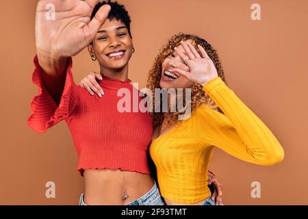 Stock Foto von fröhlichen afro Frauen posiert im Studio vor braunem Hintergrund geschossen. Stockfoto