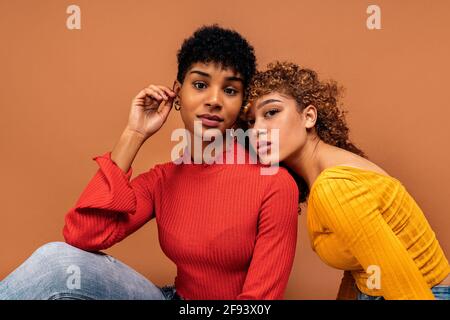 Stock Foto von schönen afro Frauen posiert im Studio vor braunem Hintergrund geschossen. Stockfoto