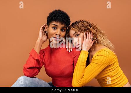 Stock Foto von schönen afro Frauen posiert im Studio vor braunem Hintergrund geschossen. Stockfoto