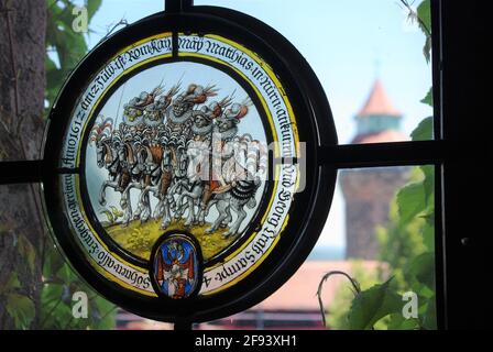 Schönes Buntglas-Rundfenster, mit Sinwell-Turm in der Ferne zu sehen, Kaiserburg, Nürnberg, Bayern, Deutschland Stockfoto