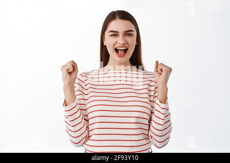 Glückliche Frau schreit und schreit vor Überfreude, siegt und erreicht Erfolg, triumphiert, Champion zu werden, feiert Sieg, gute Nachrichten, standind Stockfoto