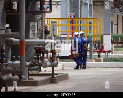 Atyrau/Kasachstan - Mai 21 2012: Petrochemische Industrie. Moderne Ölraffinerie. Zwei Arbeiter oder Ingenieure mit militärischen Gasmaskensäcken. Stockfoto