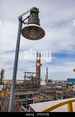 Ölraffinerie-Werk. Rot-weiß gestreifter Destillationsturm (Säule) und Teil des Raffineriekomplexes auf blauem Himmel Hintergrund. Explosionsgeschützte Lampe ein für Stockfoto