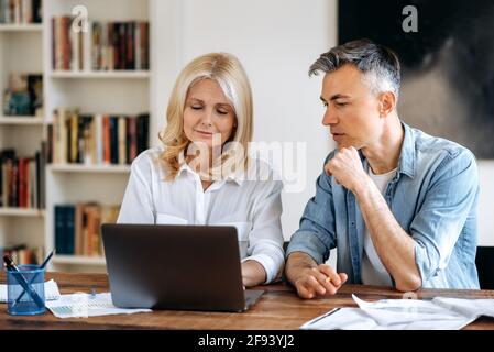Geschäftstreffen im Büro. Reifer Erfolg zwei Geschäftspartner in stilvoller Kleidung sitzen am Tisch, arbeiten an einem neuen Start-up, diskutieren Arbeitsthemen, schreiben Ideen in einem Laptop auf Stockfoto