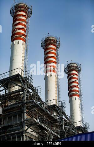 Gestreifte rote und weiße Rauchschornsteine (Pflanzenkamine) auf blauem Himmel Hintergrund. Modernes Gaskraftwerk. Nahaufnahme. Stockfoto