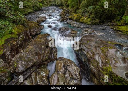 Malerischer Blick auf einen Bach, der über Felsen in der Nähe von Milford fließt Sound im Fiordland National Park auf der Südinsel Neuseelands Stockfoto