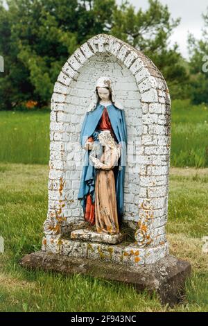 Eine madonna mit Kind in einem verlassenen alten Kirchhof. Stockfoto