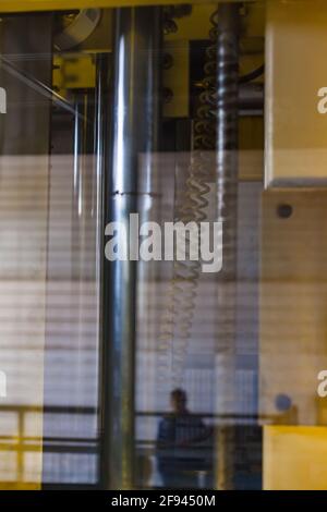 Abstrakter industrieller Hintergrund. Reflexion von Maschinenteilen in Glas. Produktionslinie von Pflasterfliesen. Stockfoto