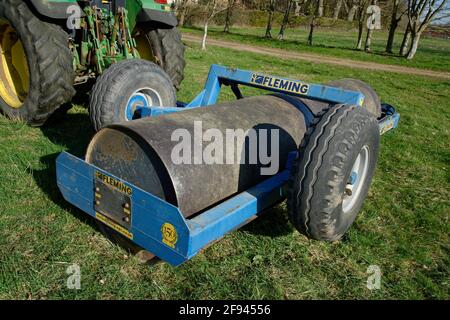 Ein Traktor mit einer schweren 5-Tonnen-Rolle wurde zurückgezogen. Eine Aufgabe, die im Frühjahr auf dem Bauernhof erledigt werden muss. Stockfoto