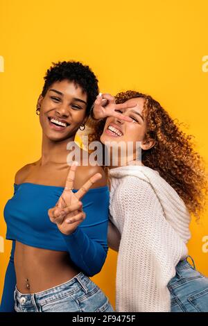 Stock Foto von fröhlichen afro Frauen mit Spaß im Studio vor gelbem Hintergrund geschossen. Stockfoto