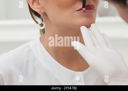 Die Kosmetikerin, die permanent Make-up auf die Lippen anwendet, macht Markierungen. Copyspace Stockfoto