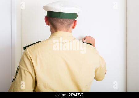 Polizist klopft an die Haustür des Hauses Stockfoto