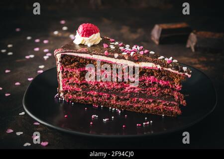 Ein Stück Himbeer-Schokoladen-Torte auf einem schwarzen Teller Dunkelbrauner Hintergrund Stockfoto