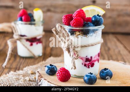 Joghurt mit Beeren und Getreide in einem Glas auf einem Rustikaler Holztisch Stockfoto