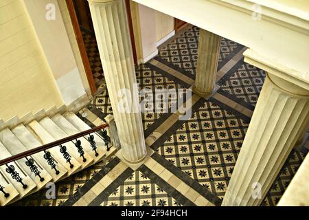 Innenansicht des neoklassizistischen Rathauses mit spektakulären ionischen Säulen, einer Marmortreppe und einem Vintage-Fliesenboden auf der griechischen Insel Syros. Stockfoto