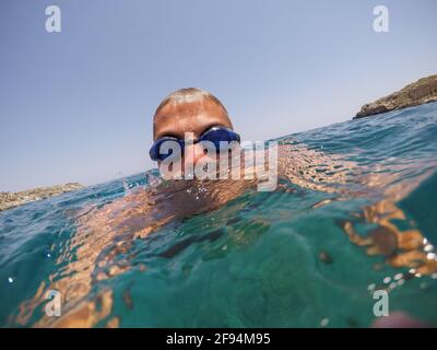 Nahaufnahme eines jungen Mannes, der an einem sonnigen Sommertag im exotischen Meer in der Nähe des Meeres schwimmt. Stockfoto