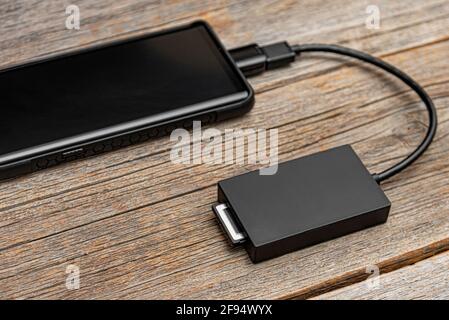 Eine Speicherkarte oder eine externe Festplatte ist über ein OTG-Kabel mit dem Smartphone verbunden. Stockfoto