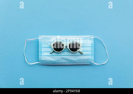 Sonnenbrille auf einer schützenden Gesichtsmaske. Sommerferienkonzept Stockfoto