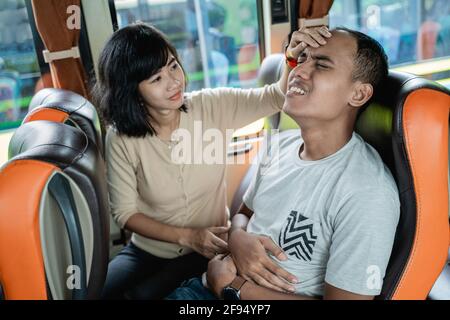 Ein Mann ist krank und eine Frau hält ihre Stirn Während Sie auf einer Busbank sitzen Stockfoto