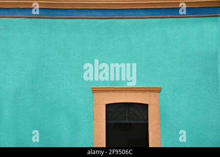 Kolonialhaus-Fassade mit venezianischer Stuckwand und einem steinernen Fenster in Santiago de Querétaro, Mexiko. Stockfoto