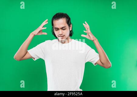 Schöner asiatischer Mann mit einem flatschigen Gesichtsausdruck Während Sie zwei Hände seitlich am Kopf anheben Stockfoto