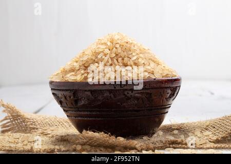 Kerala Matta Reis  Parboiled Reis oder Palakadan matta oder rot Reis in einer Holzschüssel angeordnet, die auf gelegt wird Ein Jutetuch mit weißer Hintergrundfarbe Stockfoto