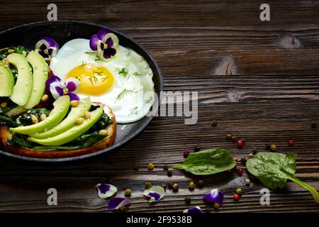 Sandwich mit Avocado, Spinat und Spiegelei in einer Pfanne. Stockfoto