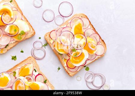 Leckere Sandwiches mit weichem Frischkäse, Radieschen, Eiern und Zwiebeln. Draufsicht. Stockfoto