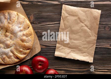Apfelkuchen auf einem rustikalen Holztisch. Draufsicht. Stück Kraftpapier leer Platz für Text. Stockfoto